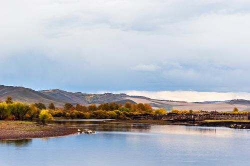 Free Breathtaking autumn landscape showcasing a tranquil river flowing through rolling hills with vibrant foliage. Stock Photo