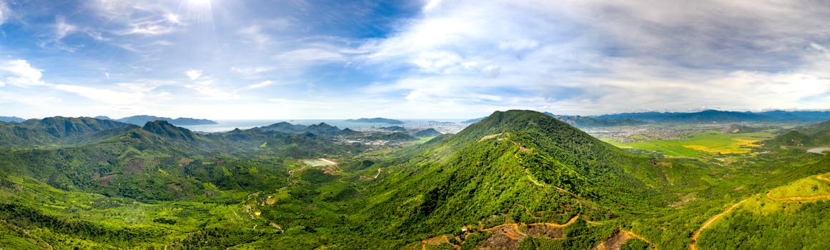 Panoramic aerial view of vibrant green mountains under a clear blue sky.