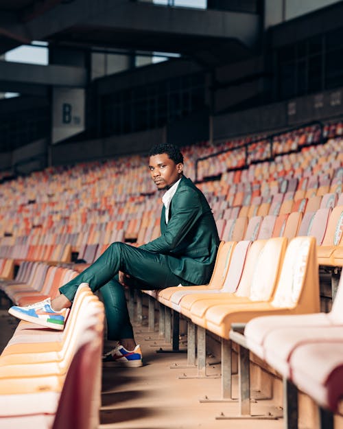 A Man in Green Suit Sitting on Bleachers