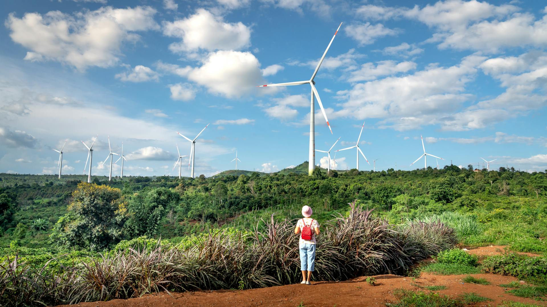 Girl in White Shirt and Pink Pants Standing on Brown Dirt Road Between Green Grass Field