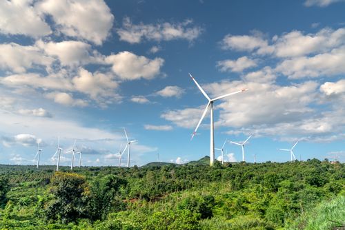 Free Wind turbines in a lush green landscape under a bright sky, showcasing renewable energy. Stock Photo