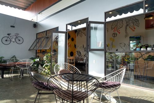 Free Sunlit modern patio with stylish furniture and artistic wall decor at a cafe. Stock Photo