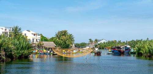 Free Scenic view of a tropical village by the river with boats and traditional fishing nets. Stock Photo