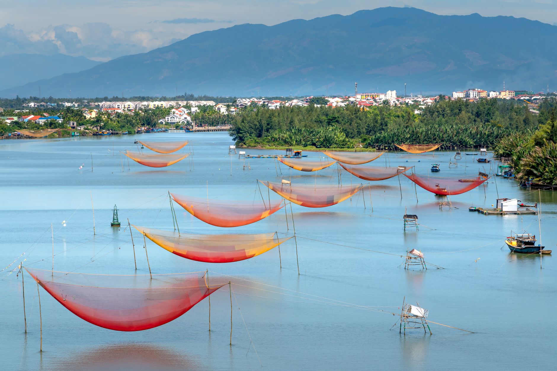 Scenic view of vibrant fishing nets over a calm lake with mountains in the background.