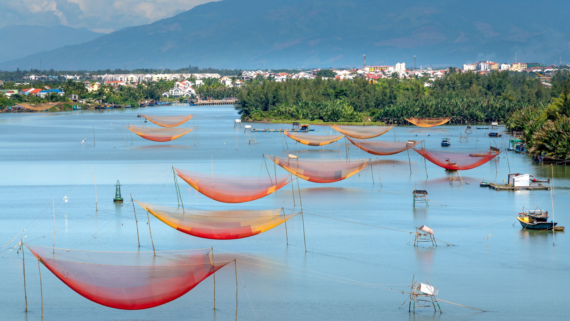 Scenic view of vibrant fishing nets over a calm lake with mountains in the background.