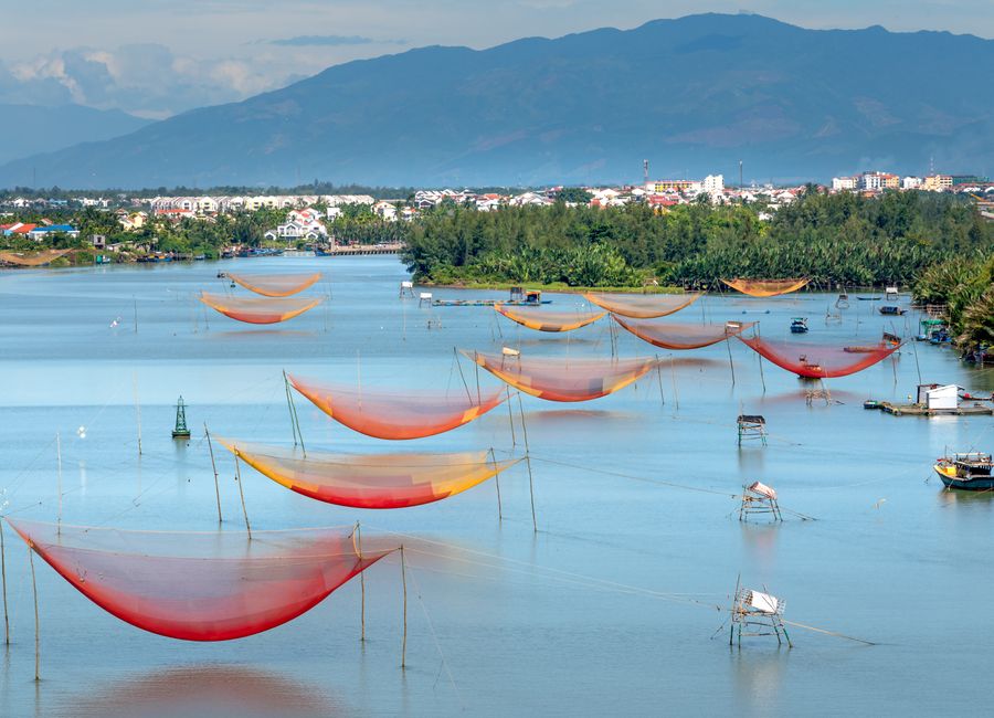 Scenic view of vibrant fishing nets over a calm lake with mountains in the background.