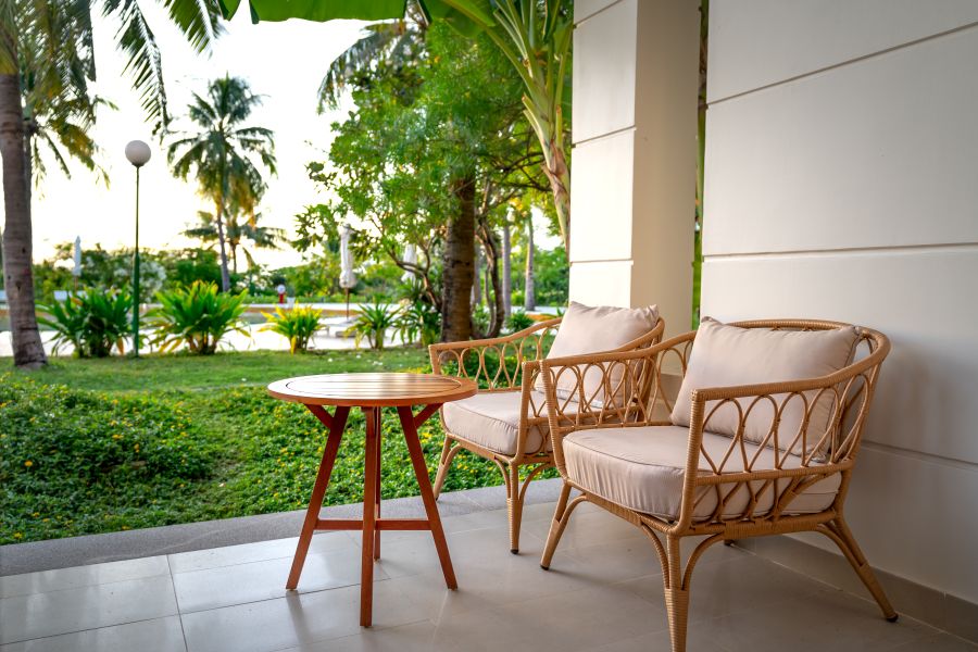 Rattan patio chairs and side table on a shaded porch — photo by Quang Nguyen Vinh on Pexels