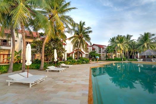 Relaxing poolside view with coconut trees and villas at a tropical resort.