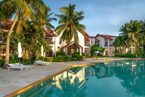 Free Explore a luxurious tropical resort featuring palm trees and an inviting poolside setting, perfect for leisure and relaxation. Stock Photo
