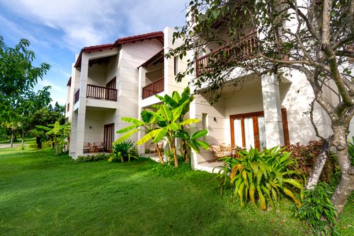 Free A contemporary residential building with a lush green lawn and tropical plants. Stock Photo