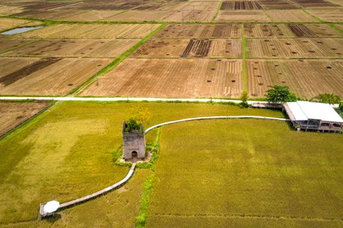 Free Aerial photo capturing lush fields and an ancient tower in a rural landscape. Stock Photo