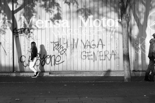 Free Monochrome image of people walking past graffiti on a city street in bright daylight. Stock Photo