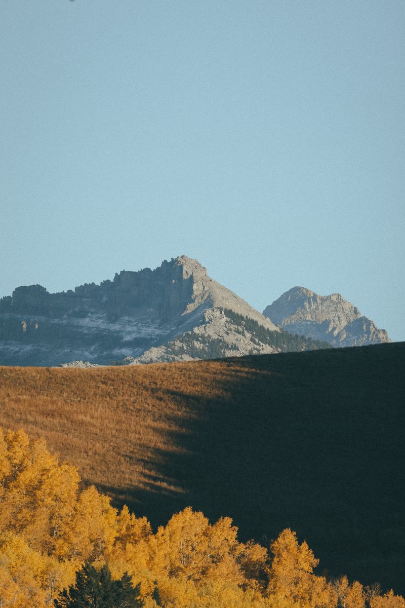 Scenic view of rock mountains with autumn trees against a blue sky.