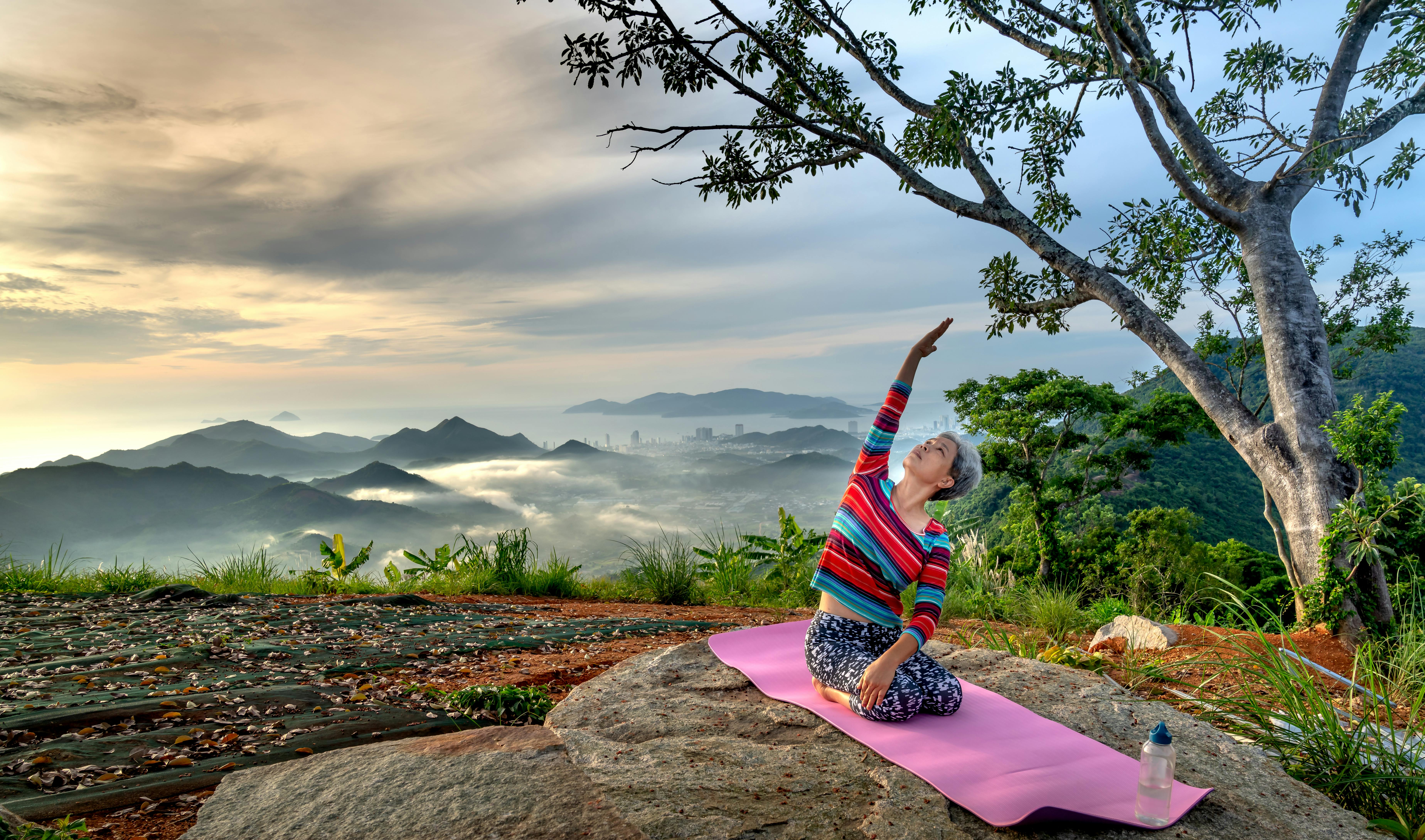 an elderly woman doing yoga on the mountain