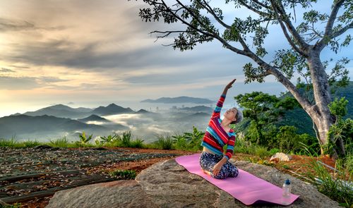 Free Elderly woman doing yoga on mountain top at sunrise, embracing healthy living. Stock Photo