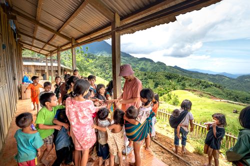 Free A group of children gather on a terrace overlooking rolling hills and mountains on a sunny day. Stock Photo