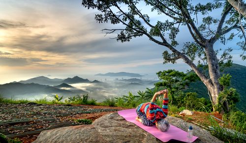 Free Elderly woman performing yoga on a mountain with a breathtaking view, promoting active and healthy lifestyle. Stock Photo