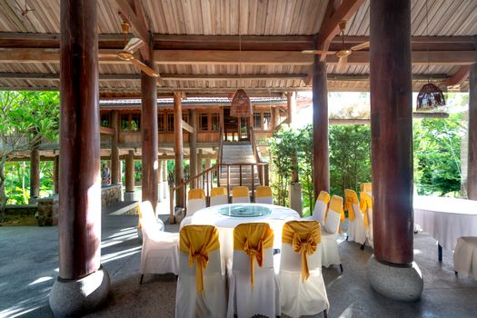 Beautifully arranged banquet setting in an open pavilion with rustic wooden pillars and lush garden views.