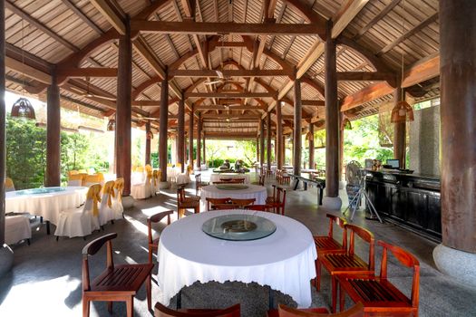 Spacious covered dining area with wooden beams and elegantly set tables in a pavilion style.