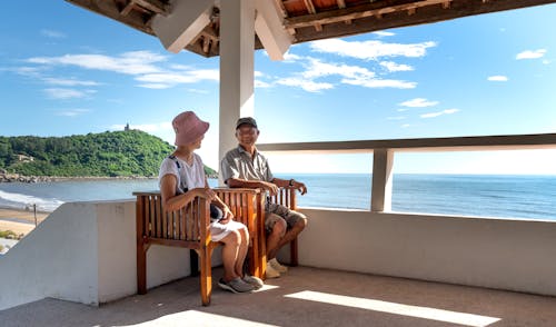 A Man and Woman Sitting on the Wooden Chairs