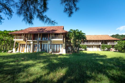 Charming tropical resort showcasing lush greenery and palm trees under a clear blue sky.