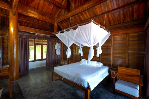 Free A cozy bedroom with wooden decor and a white canopy bed, offering a retreat in nature. Stock Photo