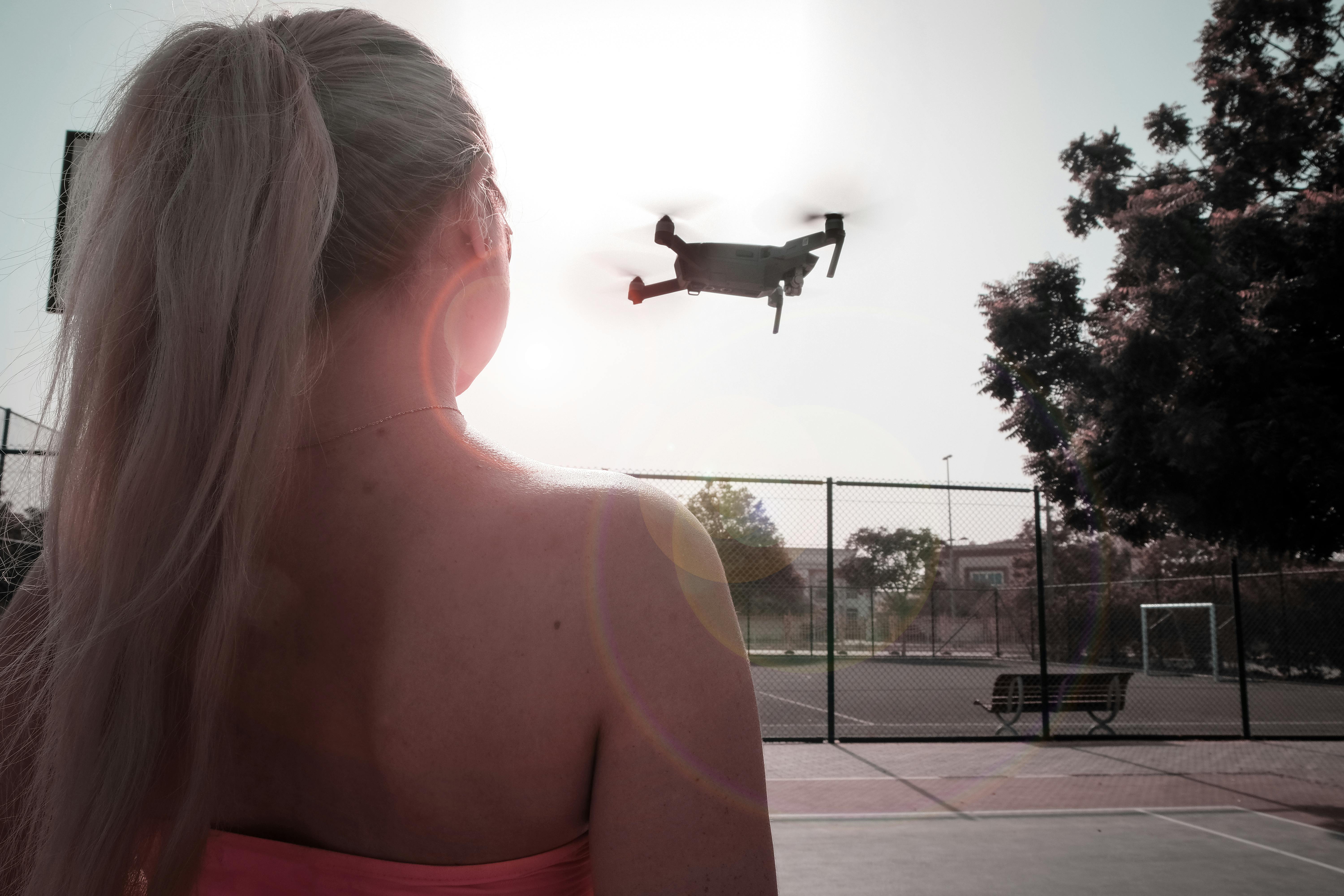 woman looking at flying drone