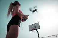 一名妇女在篮球场附近操作无人机，拍摄迪拜的鸟瞰图