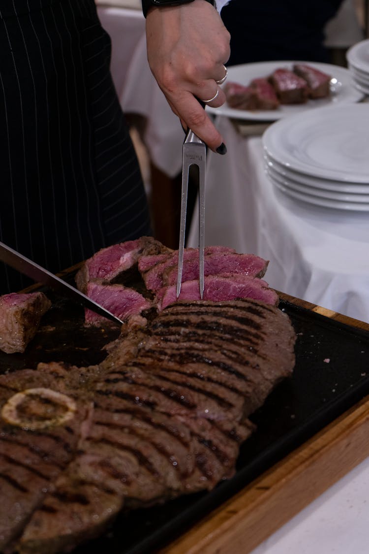 A Person Slicing The Steak 