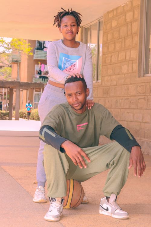 Free Young African couple in casual attire posing with a basketball outdoors. Stock Photo