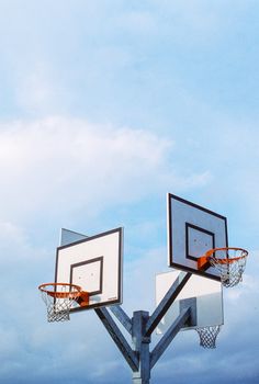 Two basketball hoops on metal poles under a vibrant blue sky, ideal for sports theme.