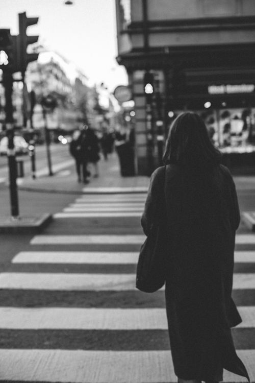 Free Black and white image of a woman crossing a zebra crossing on a city street. Stock Photo