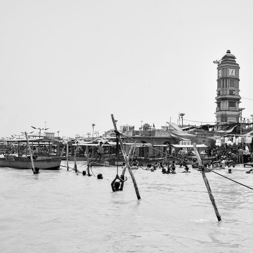 Free A vibrant riverside scene featuring a clock tower and swimmers captured in black and white. Stock Photo