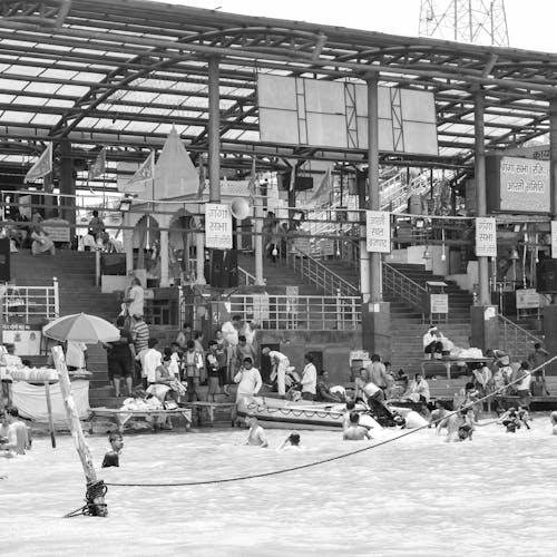 Grayscale Photography of People Swimming on the Water Near Concrete Stairs