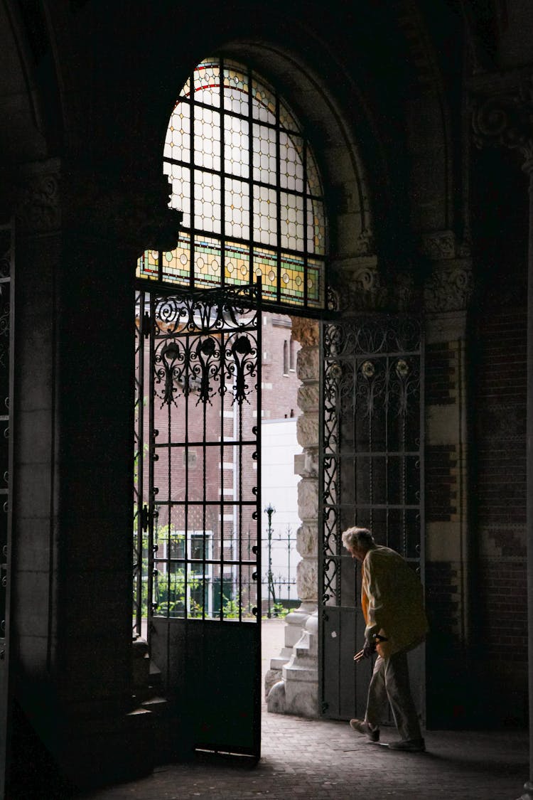 Old Woman Walking In Doors With Stained Glass Windows