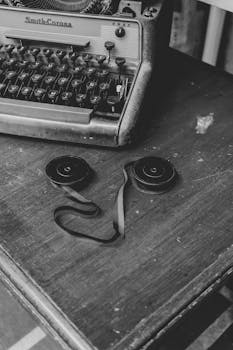 Black and white photo of a vintage typewriter with ribbon reels on a wooden desk in Mérida, Venezuela.