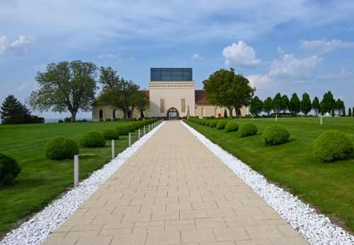 Free A beautiful estate entrance featuring a long pathway surrounded by manicured bushes and lush greenery. Stock Photo