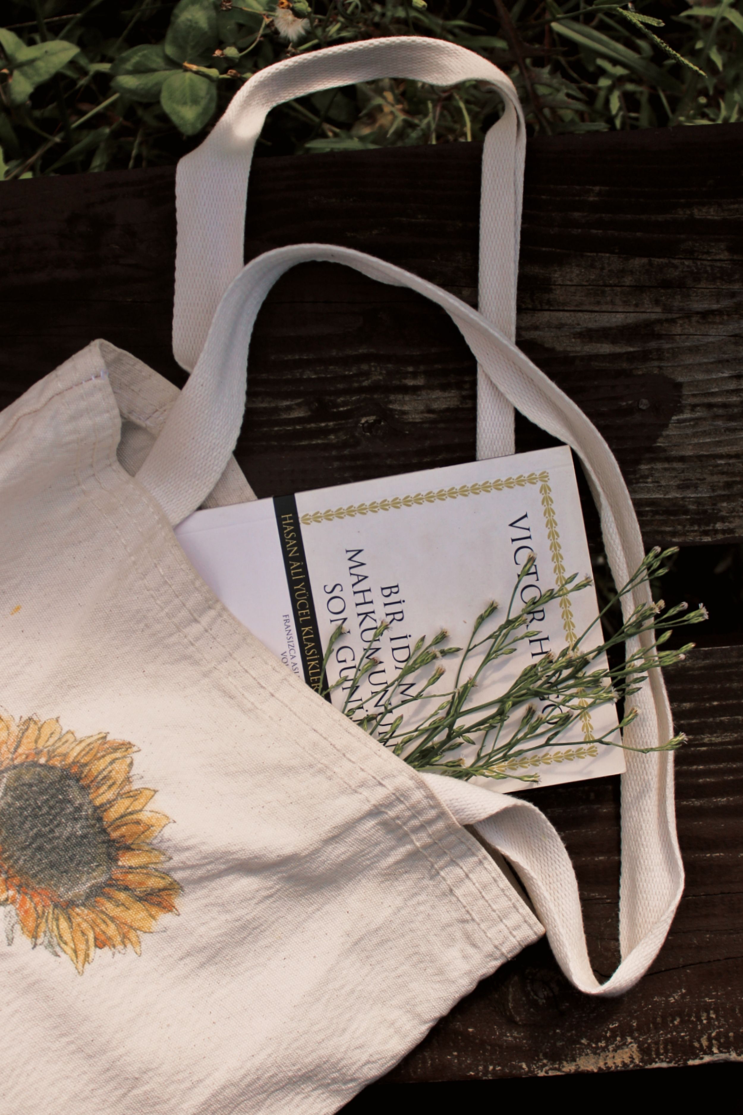 A charming still life of a tote bag with a book and dried flowers on a wooden bench. - Understanding Different Handbag Styles and Their Uses