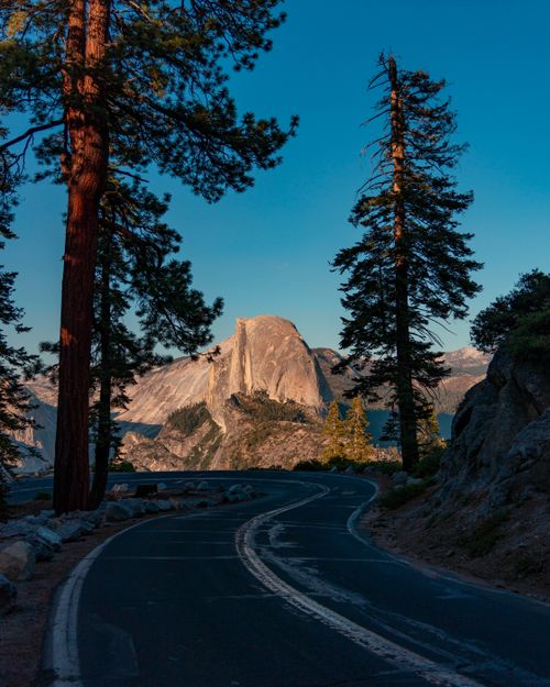 Free Winding road leading to a scenic view of Half Dome surrounded by conifer trees in Yosemite National Park. Stock Photo