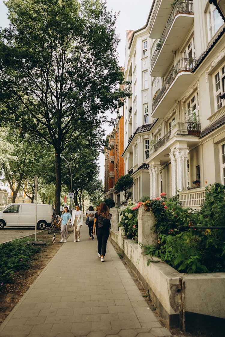 People Walking On The Sidewalk Near The Apartment Buildings