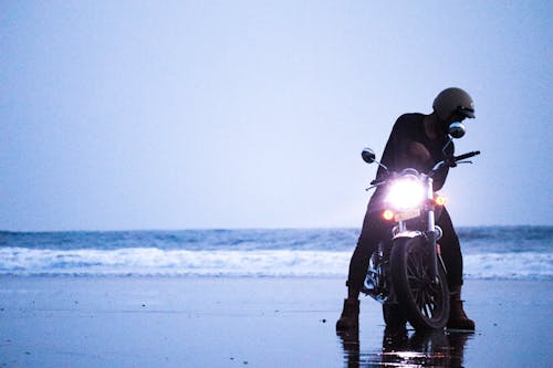A Person Sitting on the Motorcycle at the Beach 