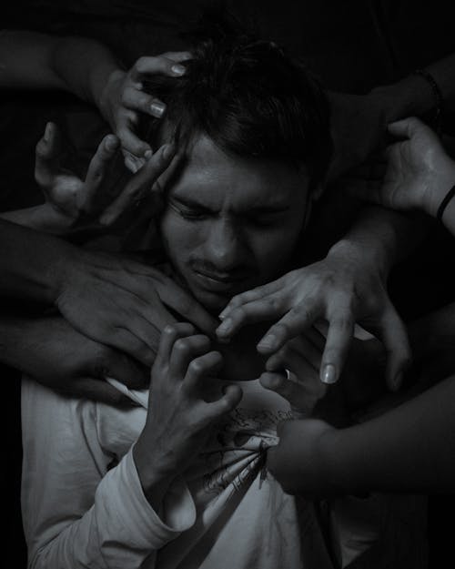 Free Grayscale Photo of a Man Surrounded by Hands  Stock Photo