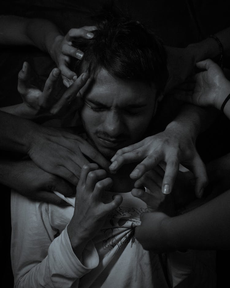 Grayscale Photo Of A Man Surrounded By Hands 