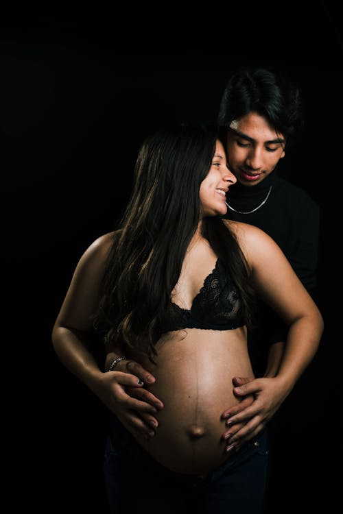 Smiling Couple Embracing in a Pregnancy Photoshoot