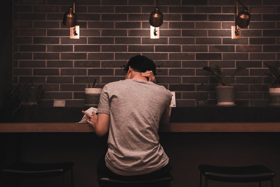 A man relaxes and reads in a stylish cafe, featuring modern decor and soft lighting.