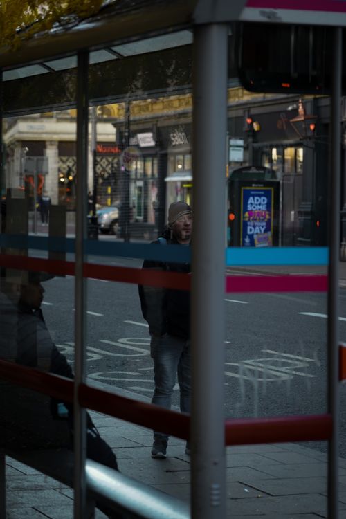Free People waiting at a bus stop in the city with reflections and urban surroundings. Stock Photo
