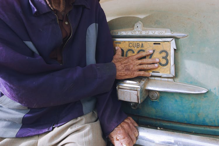 Mans Hand Touching A Licence Plate Of A Car