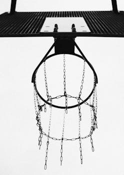 Black and white view of a chain link basketball hoop from below, emphasizing sport and simplicity.
