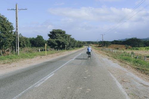 Man Riding a Bike on Asphalt Road
