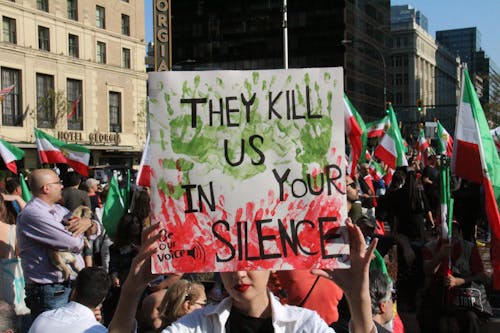 A Person Holding Placard with They Kill Us in Your Silence Message